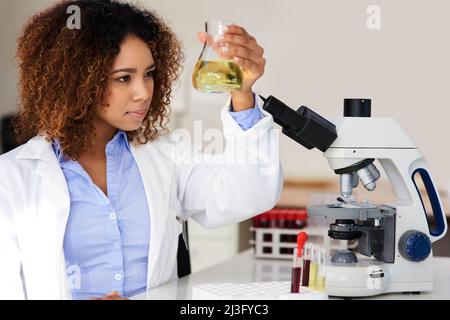 Warten, bis sich die Lösung offenbart. Ausgeschnittene Aufnahme einer jungen Wissenschaftlerin, die im Labor ein Experiment durchführt. Stockfoto