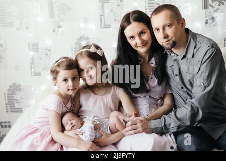 Glückliche Familie und ein neugeborenes Baby in den Händen seiner älteren Schwester. Stockfoto
