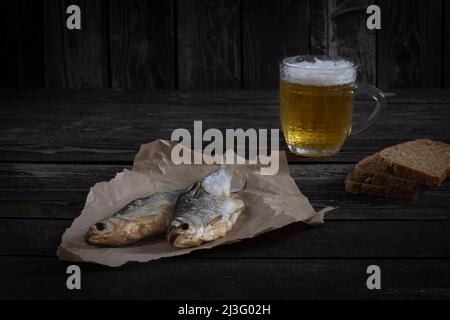 Getrockneter Flussfisch, Snacks für Bier auf dunklem Holzhintergrund im rustikalen Stil Stockfoto