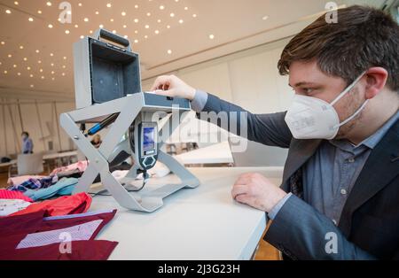 08. April 2022, Baden-Württemberg, Tübingen: Thorsten Haas, Mitarbeiter des Regierungspräsidiums Tübingen, Abteilung Marktüberwachung Baden-Württemberg, untersucht mit einem Analysator einen Babyanzug auf seine Inhaltsstoffe. Der Analysator arbeitet mit Hilfe von Röntgenstrahlen und zeigt am Ende der Elementanalyse den Inhalt des Strampelanzugs an. Foto: Christoph Schmidt/dpa Stockfoto