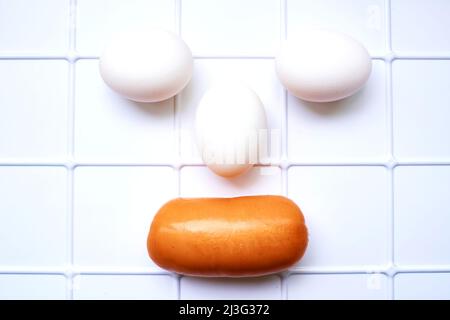 Eier und eine leckere Wurst auf einem weiß karierten Stand im Kühlschrank Stockfoto