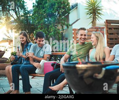 Gekühlte Hinterhof-Stimmung mit Freunden. Aufnahme einer Gruppe von Freunden, die zusammen Bier beim Barbecue trinken. Stockfoto