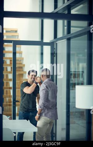 Brüder im Geschäft. Aufnahme von zwei jungen Geschäftsleuten, die in einem modernen Büro solidarisch die Hände greifen. Stockfoto