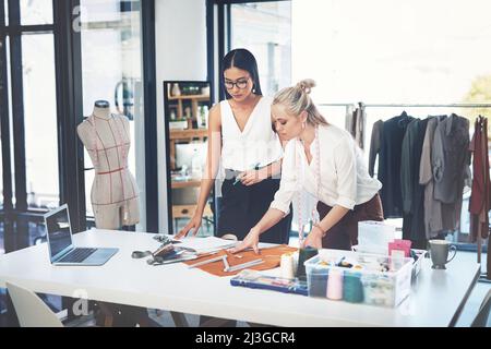 Ich brauche Ihre professionelle Meinung. Aufnahme von zwei jungen Modedesignern, die in einem Workshop zusammenarbeiten. Stockfoto