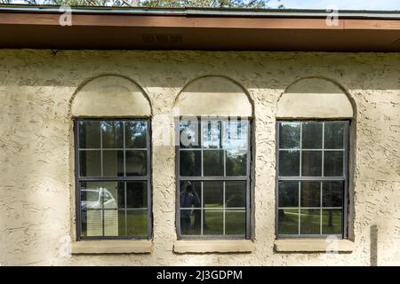 Die Seitenansicht einer braunen 1970er Jahre Ranch Stil spanischen Stil Villa Stuckstein Block Haus mit architektonischen Bögen und schwarzem Aluminium Original Stockfoto