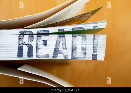LESEN! Geschrieben mit Stempelbeschriftung auf der Seite eines dicken Buches Stockfoto