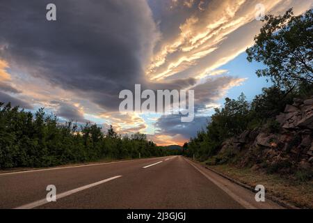 Dramatischer Himmel bei Sonnenuntergang über der Landstraße, Bosnien-Herzegowina Stockfoto