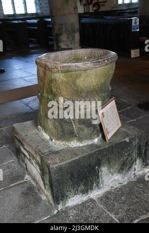 Der aus Stein gemeißelte Sächsische Font aus dem 14.. Jahrhundert in der Kirche St. Morwenna und St. Johannes der Täufer in der Pfarrei Morwenstow, Cornwall, Stockfoto