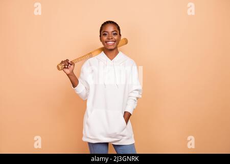 Foto von zufriedenen hübschen Mädchen Gangster halten Baseballschläger toothy Lächeln Blick Kamera isoliert auf beige Farbe Hintergrund Stockfoto