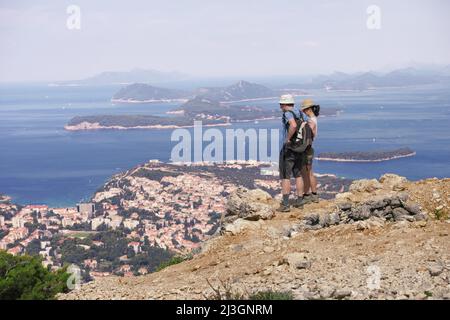 DUBROVNIK, KROATIEN - 08. JULI 2018: Ein Paar Wanderer auf dem Gipfel des SRD-Gebirges mit Blick auf die großartige Meereslandschaft der Häuser und Küste von Dubrovnik Stockfoto