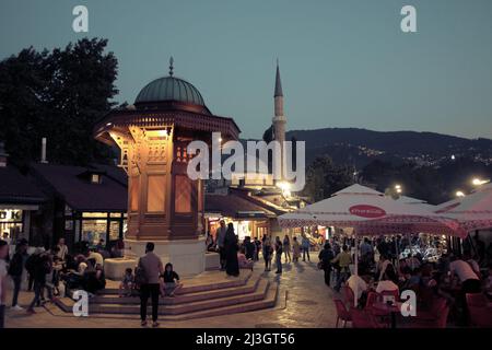 SARAJEVO, BOSNIEN UND HERZEGOWINA - 14. JULI 2018: Touristen in der Dämmerung auf dem Platz des Holzbrunnens von Sebilj im Zentrum von Bascarsija Stockfoto