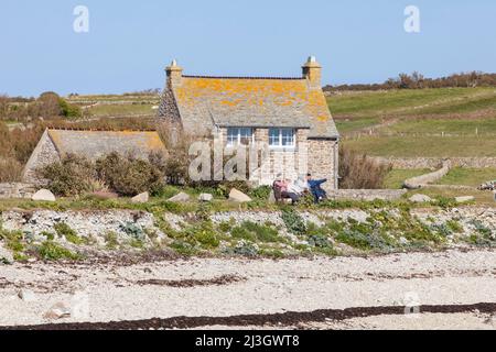 Frankreich, Manche, Cotentin, Cape Hague, Auderville, Goury Harbour, eine kleine Gruppe von Freunden, die sich auf einer Bank vor einem traditionellen Steinhaus ausruhen und unterhalten Stockfoto