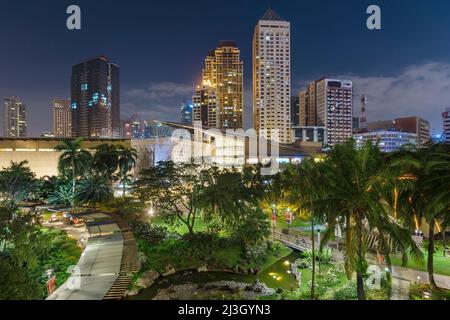 Philippinen, Metro Manila, Makati District, Blick auf die Greenbelt Mall bei Nacht und beleuchtete Wolkenkratzer im Hintergrund Stockfoto