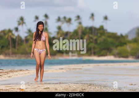 Philippinen, Palawan, El Nido, Bacuit-Archipel, Vigan Island, Eine junge philippinische Frau, die auch Snake Island genannt wird, geht auf der Sandbank in Form einer Schlange, die Zugang zur Insel bietet Stockfoto