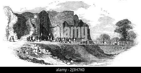 The Rhuddlan Royal Eisteddvod - Rhuddlan Castle, [in Wales], 1850. Blick auf '...das Äußere von Rhuddlan Castle von der St. Asaph Seite der Brücke. Die westlichen Türme sind abgebildet...die Burg, oder besser gesagt die Ruinen, ist quadratisch, mit sechs Türmen. Der ursprüngliche Gründer war Prinz Llewelyn AP Seisyllt, im Jahr 1020 ... die Burgruinen bedecken etwa zweieinhalb Hektar; und die hohen westlichen Mauern, bedeckt mit Moos und Efeu, haben einen sehr malerischen Aspekt. Unser Künstler hat das Portcullis am südöstlichen Eingang eingraviert. Über dem Graben wurde eine Holzbrücke für die Besucher errichtet. Kabinen und Stockfoto