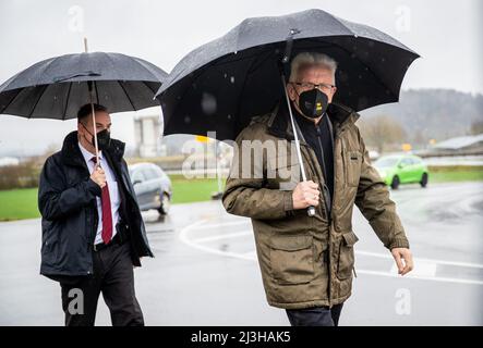 08. April 2022, Baden-Württemberg, Tübingen: Gefolgt von einem seiner Leibwächter, Winfried Kretschmann (r, Bündnis 90/die Grünen), Ministerpräsident von Baden-Württemberg, trifft im Solarpark Lustnauer Ohren ein. Foto: Christoph Schmidt/dpa Stockfoto