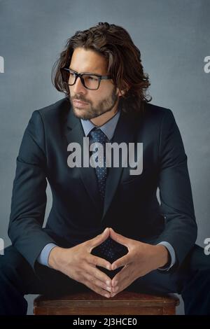 Ein Gentleman zu sein, zeigt sich in deinem Aussehen. Studioaufnahme eines gut gekleideten Geschäftsmanns vor grauem Hintergrund. Stockfoto