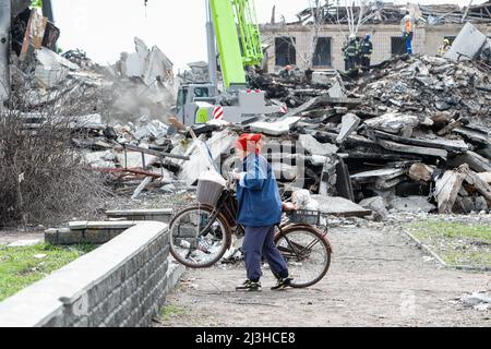 8. April 2022, Borodjanka, Rajon Bucha im Gebiet Kiew, Ukraine: Eine ältere Frau geht mit ihrem Fahrrad in die Nähe des Wracks eines beschädigten Wohngebäudes, das die russischen Luftangriffe im Borodjanka-Bezirk Bucha im Kiewer Gebiet nach den russischen Luftangriffen auf das Gebiet verursacht haben, als die ukrainischen Streitkräfte die Stadt zurückgeholt haben. (Bild: © Daniel Ceng Shou-Yi/ZUMA Press Wire) Stockfoto