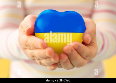 Kinderhände mit Herz und ukrainischer Flagge.Friedenskonzept.die Kinder bitten um Frieden. Es gibt keinen Krieg. Betet für die Ukraine. Rettet Die Ukraine Stockfoto