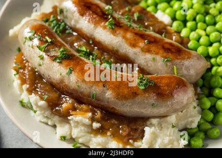 Hausgemachte britische Bangers und Maische mit Zwiebelsoße Stockfoto