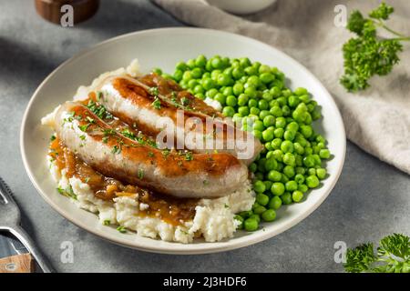 Hausgemachte britische Bangers und Maische mit Zwiebelsoße Stockfoto