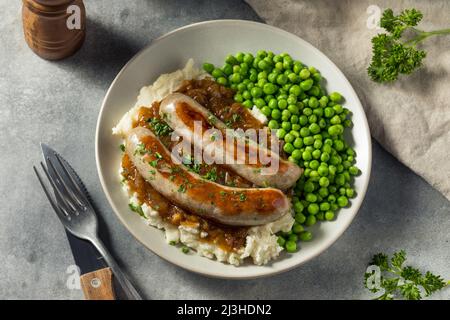 Hausgemachte britische Bangers und Maische mit Zwiebelsoße Stockfoto