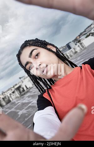 Stellen Sie sich vor, ich rollte. Ein beschnittenes Porträt einer attraktiven jungen Tänzerin, die ein Selfie macht, während sie vor stürmischer Kulisse auf einem Dach steht. Stockfoto