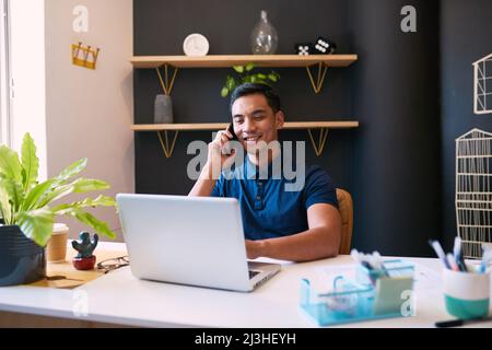 Eine große Aufnahme eines jungen Geschäftsmannes, der in einem trendigen Büro an seinem Schreibtisch einen Anruf entgegennimmt Stockfoto