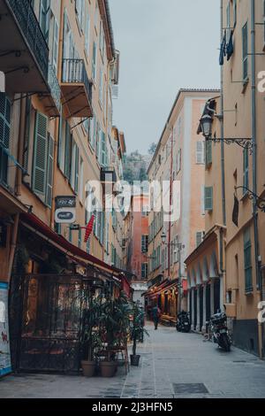 Nizza, Frankreich - 10. März 2022: Blick auf Restaurants in einer schmalen Straße in der Altstadt von Nizza, einem berühmten Touristenziel an der französischen Riviera. Stockfoto