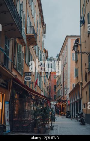 Nizza, Frankreich - 10. März 2022: Blick auf Restaurants in einer schmalen Straße in der Altstadt von Nizza, einem berühmten Touristenziel an der französischen Riviera. Stockfoto