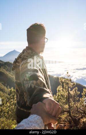 Paar auf einem Berg, Mann, der den Horizont mit der Hand der Frau betrachtet, Konzept - Reisen, Lifestyle, Liebe, Freiheit, Natur, Zweisamkeit Stockfoto