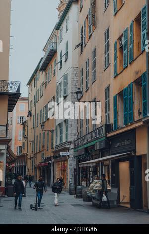 Nizza, Frankreich - 10. März 2022: Menschen, die an den Geschäften in der Altstadt von Nizza vorbeilaufen, einem berühmten Touristenziel an der französischen Riviera. Stockfoto