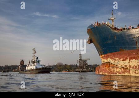 Ein Schlepper zieht ein Containerschiff in Position Stockfoto