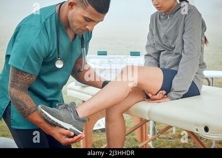 Alle Schmerzen. Zugeschnittene Aufnahme eines hübschen jungen männlichen Physiotherapeuten, der draußen an einer weiblichen Patientin arbeitet. Stockfoto