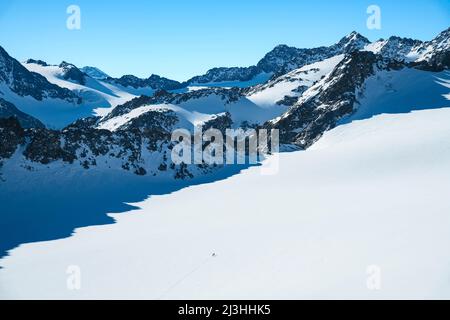 Zwei Bergsteiger im Winter verschneite Hochberge auf dem Lüsenser Ferner an einem sonnigen Tag. Gletscher und felsige Gipfel unter blauem Himmel. Stubaier Alpen, Tirol, Österreich, Europa Stockfoto
