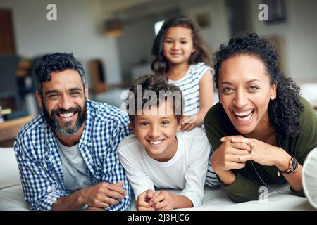 Quality Time stärkt ihre familiäre Bindung. Porträt einer glücklichen Familie, die sich zu Hause verbindet. Stockfoto