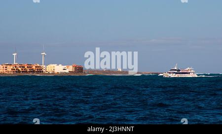 Spanien, Kanarische Inseln, Fuerteventura, Segeltörn, Insel Los Lobos, Naturschutzgebiet, Ausflugsboot fährt in den Hafen von Corralejo, links Windturbinen im Bild, Schiff rechts, himmelblau, vereinzelt Wolken Stockfoto