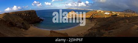 Kanarische Inseln, Lanzarote, Vulkaninsel, Stimmung nach dem Gewitter, Papagallo-Strände, Menschenleer, himmelblau mit Wolken grau-weiß, Morgenlicht, 180- Grad-Panorama aus der Sicht des Strandes, Felsen auf der einen Seite glänzen durch Morgenlicht, Gebäude im Morgenlicht, offenes Meer und Lanzarotes Küste im Hintergrund Stockfoto