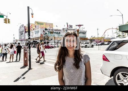 SURF Ave/STILLWELL AV, New York City, NY, USA, 14 Jahre alt, kaukasisches Teenager-Mädchen mit braunen Haaren an einer Kreuzung in Coney Island Stockfoto