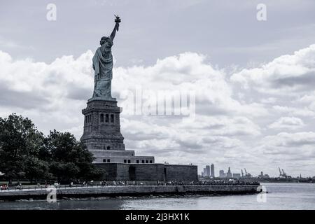 Liberty Island FERRY, New York City, NY, USA, Blick auf die Insel der Freiheit mit Freiheitsstatue von der Fähre auf dem Hudson River aus gesehen, Symbol der New York City Freiheitsstatue und einem dramatischen Himmel Freiheitsstatue vor blauem Himmel mit wunderschönem Wolkenhintergrund Stockfoto