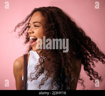 Nichts wird mich heute zu Boden bringen. Studioaufnahme einer schönen jungen Frau, die vor einem rosa Hintergrund posiert. Stockfoto