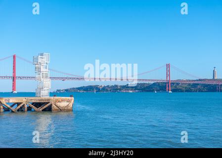 Statue mit Hintergrund, bestehend aus Brücke vom 25.. April und Nationalheiligtum von Cristo Rei in Lissabon, Portugal. Stockfoto