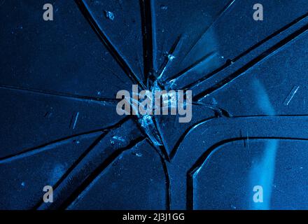 Nahaufnahme der Fototextur von blauem gebrochenem und rissem Glas auf schwarzem Hintergrund. Stockfoto