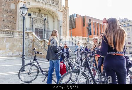 Weibliche Touristen auf Fahrrädern mit einem Reiseleiter in San Jeronimo de Real, im Zentrum von Madrid, Spanien. Radtouren in Europa Stockfoto