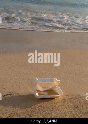 Wegwerfplatte an einem schönen Strand mit Sonnenuntergang, blauem Wasser und sauberem Sand hinterlassen Stockfoto