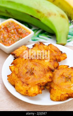 Patacone oder Tostones aus grünem oder reifer Kochbanane, mit einer knusprigen Textur, begleitet von einem Tomaten- und Zwiebeleintopf namens „Hogado“. Traditionell Kolumbianisch Stockfoto
