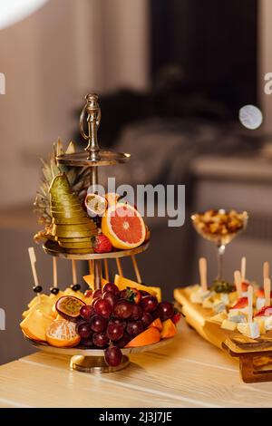 Sortiment tropischer Früchte auf weißem Teller mit frischem Saft, textiler grauer Hintergrund. Draufsicht. Stockfoto