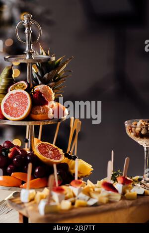 Frisches Obst auf dem Teller auf dem Holztisch. Vielfalt an geschnittenen Früchten. Verschiedene Früchte. Kiwis, Trauben, Orange, Bananen, Äpfel, Birnen. Stockfoto