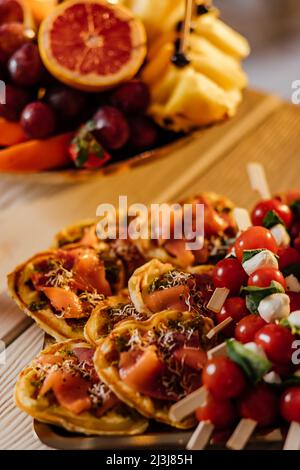 Canapes Food-Auswahl und Dessert auf Tellern. Traubenbeeren mit Käse und Shrimps mit Sauce, Erdbeeren mit Minze und Marmelade in Tassen, leckere FIS Stockfoto