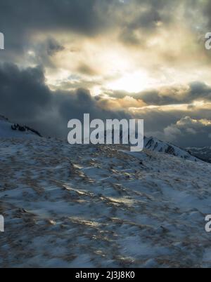 Die Sonne bricht durch die Wolken über der winterlichen Berglandschaft. Nagelfluhkette, Allgäuer Alpen, Bayern, Deutschland